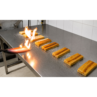 Bars of turrón de yema being toasted with a flame on a steel table at Laura Colomina Masiá